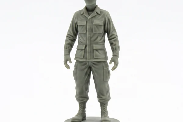 Precise, clean 3/4 profile photograph of a smooth, unpainted grey-green soldier figurine with a campaign hat, centered on a pure white background with a soft, diffuse grounding shadow.
